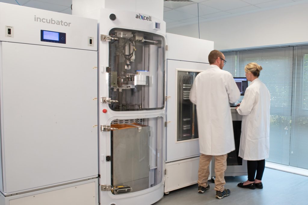 Two researchers discussing autonomous cell culture system UI.