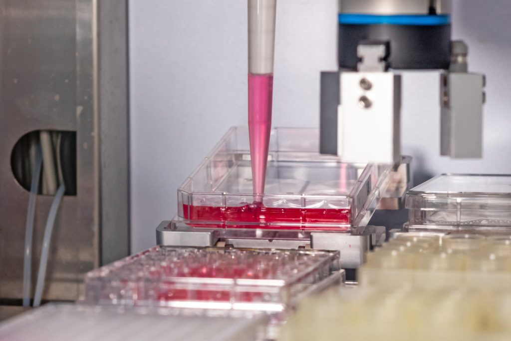 Automated liquid handler removing nutrient medium from cell culture plate in autonomous system.