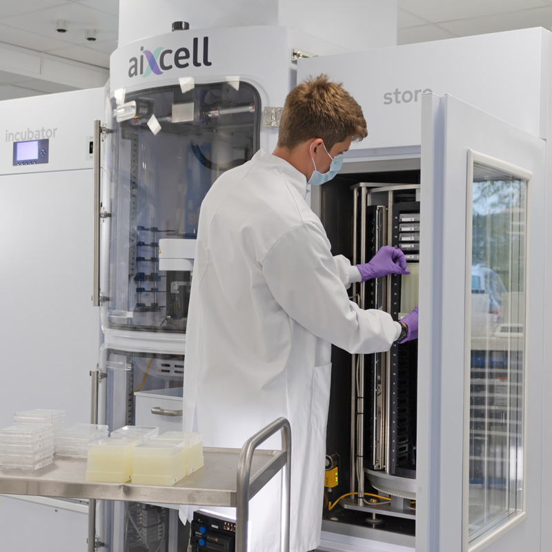 Researcher loading consumables like fresh plates and pipette tip boxes into autonomous cell culture system.